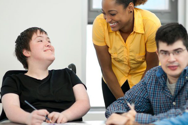 A teacher speaks with a student in a wheelchair