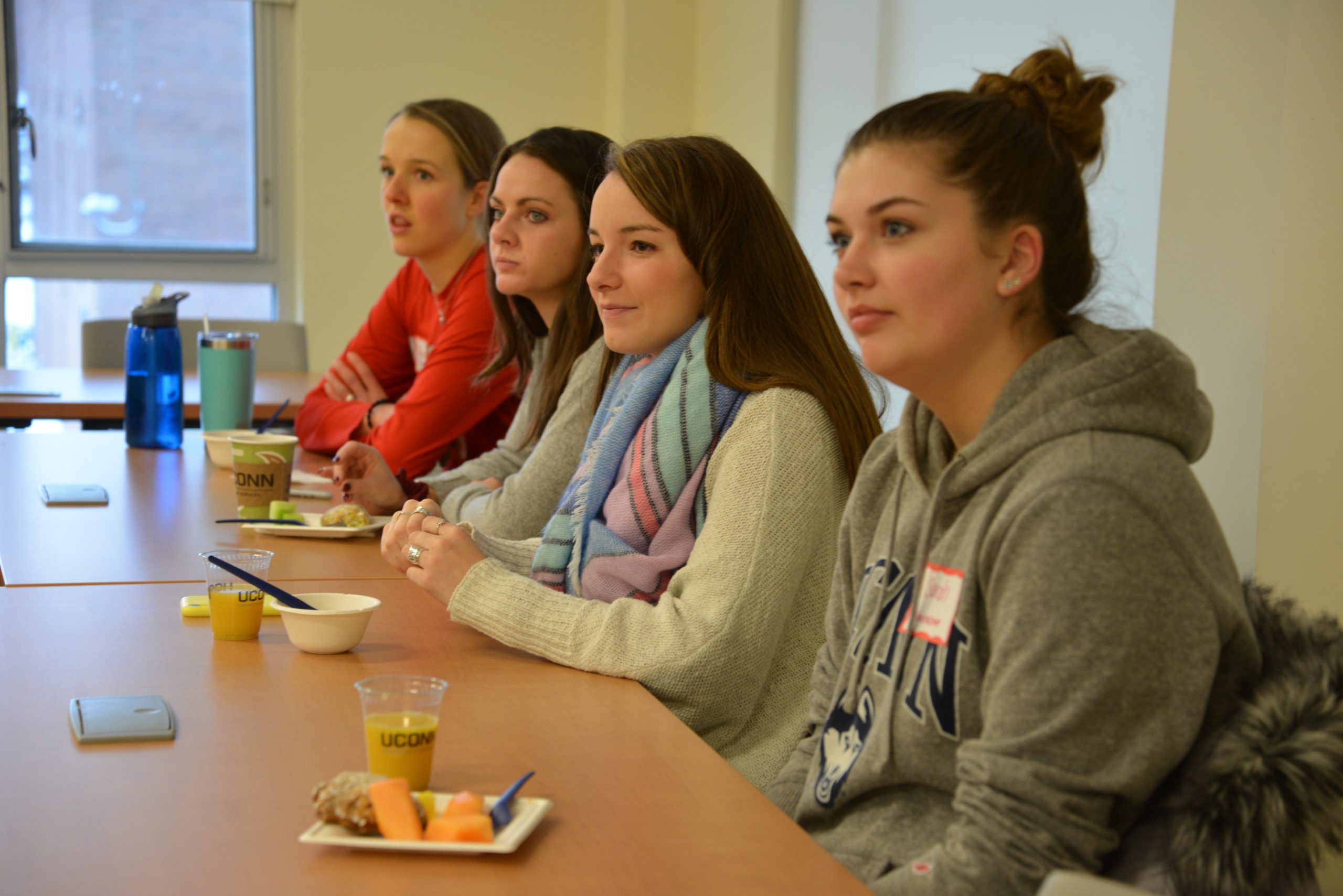 Four white women sit in a row at a table.